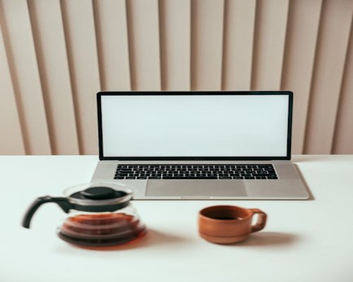 A laptop on a clean desk with a warm beverage emphasizing a mindful break at work